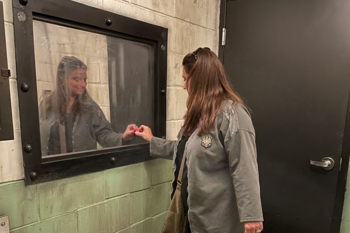 woman in jail cell looking at mirror