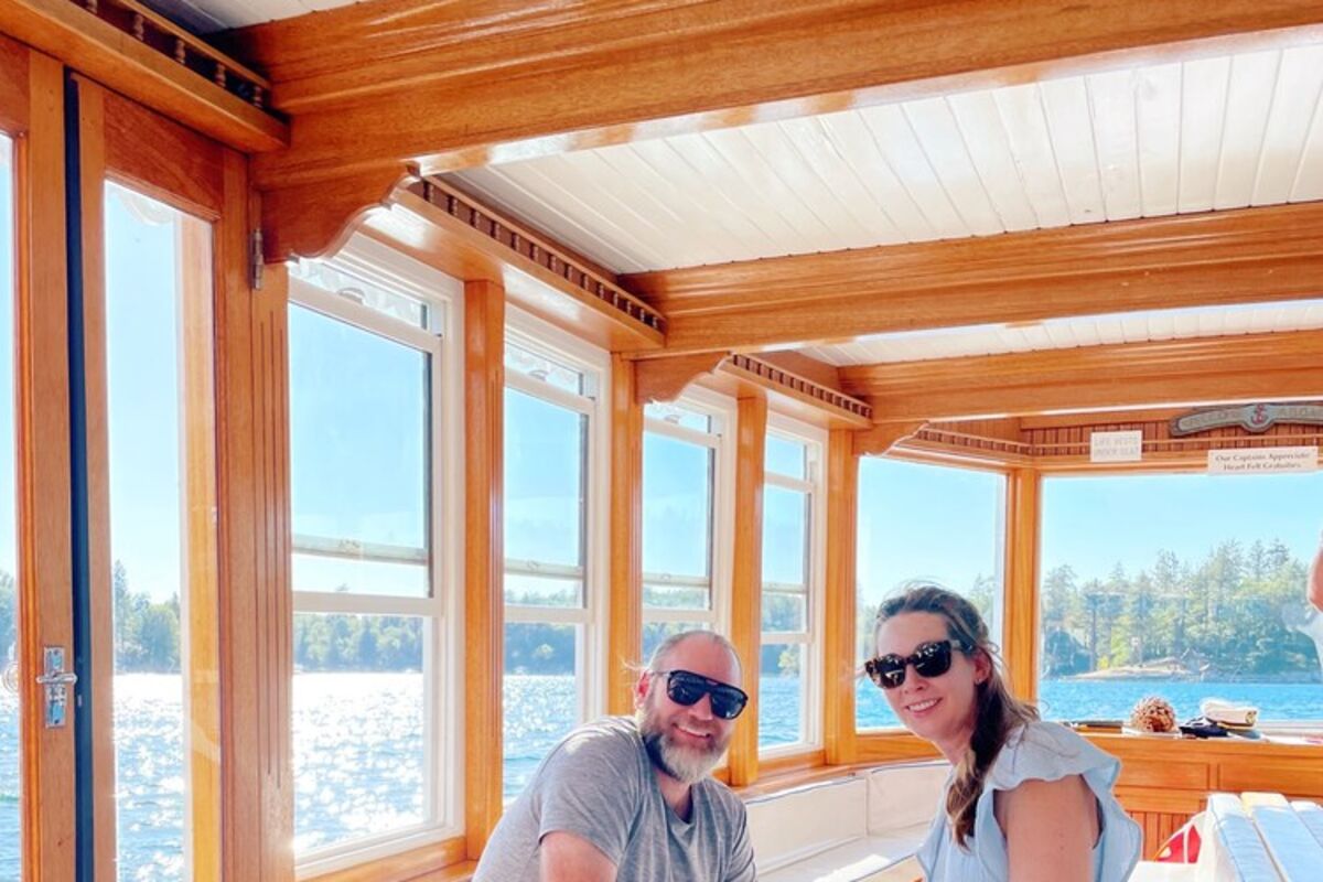 A couple and dog sitting on a boat in a lake.