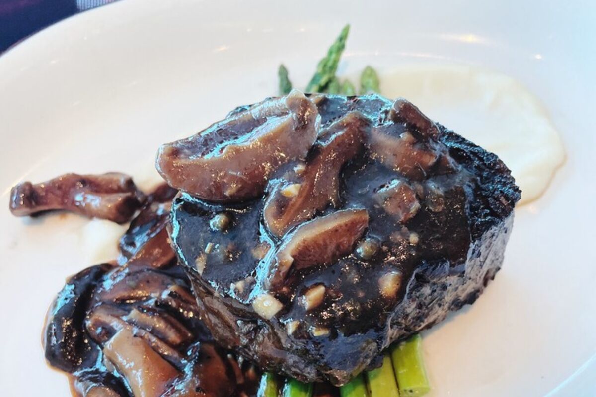 Steak with peppercorn sauce and mushrooms over asparagus.