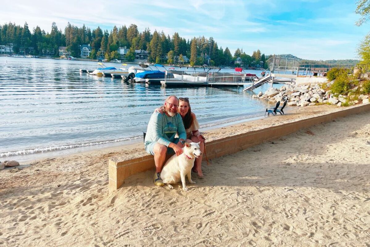 couple sitting on beach with dog