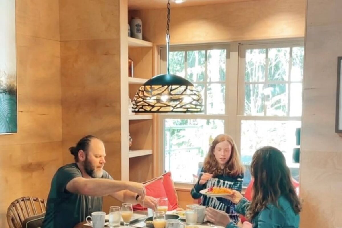 Three people eating breakfast at a table inside a bungalow in Hawaii.