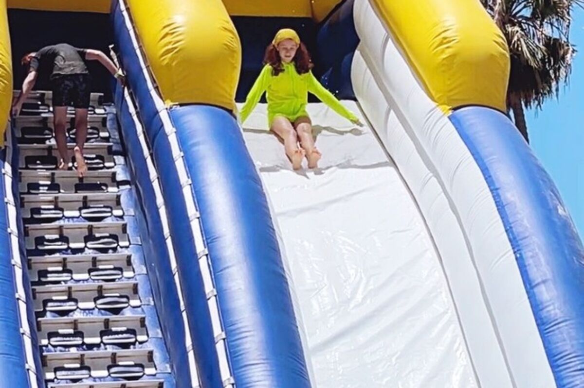 An inflatable giant waterslide two stories tall with a girl sliding down.