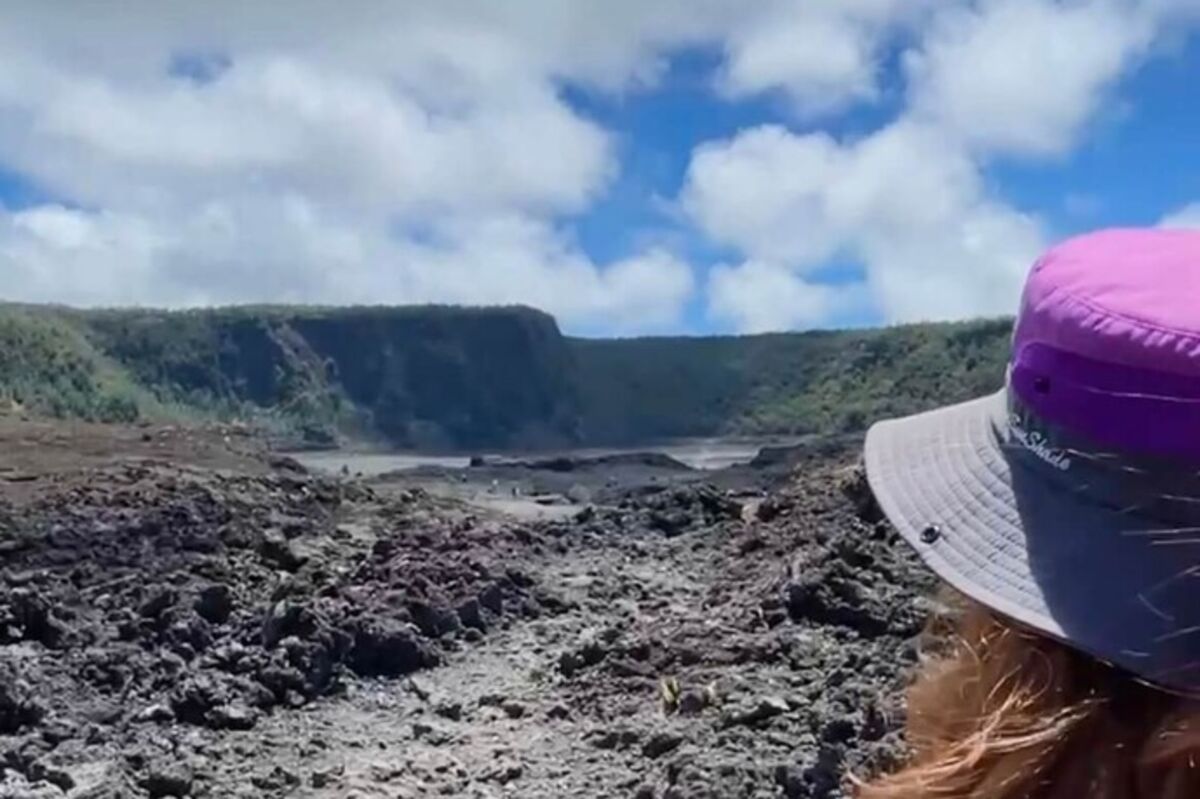 A girl looking back to a giant caldera of hardened lava in Hawaii.