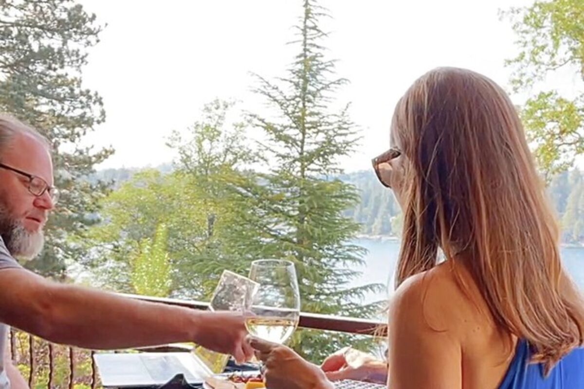 Couple sitting on balcony eating charcuterie and drinking wine