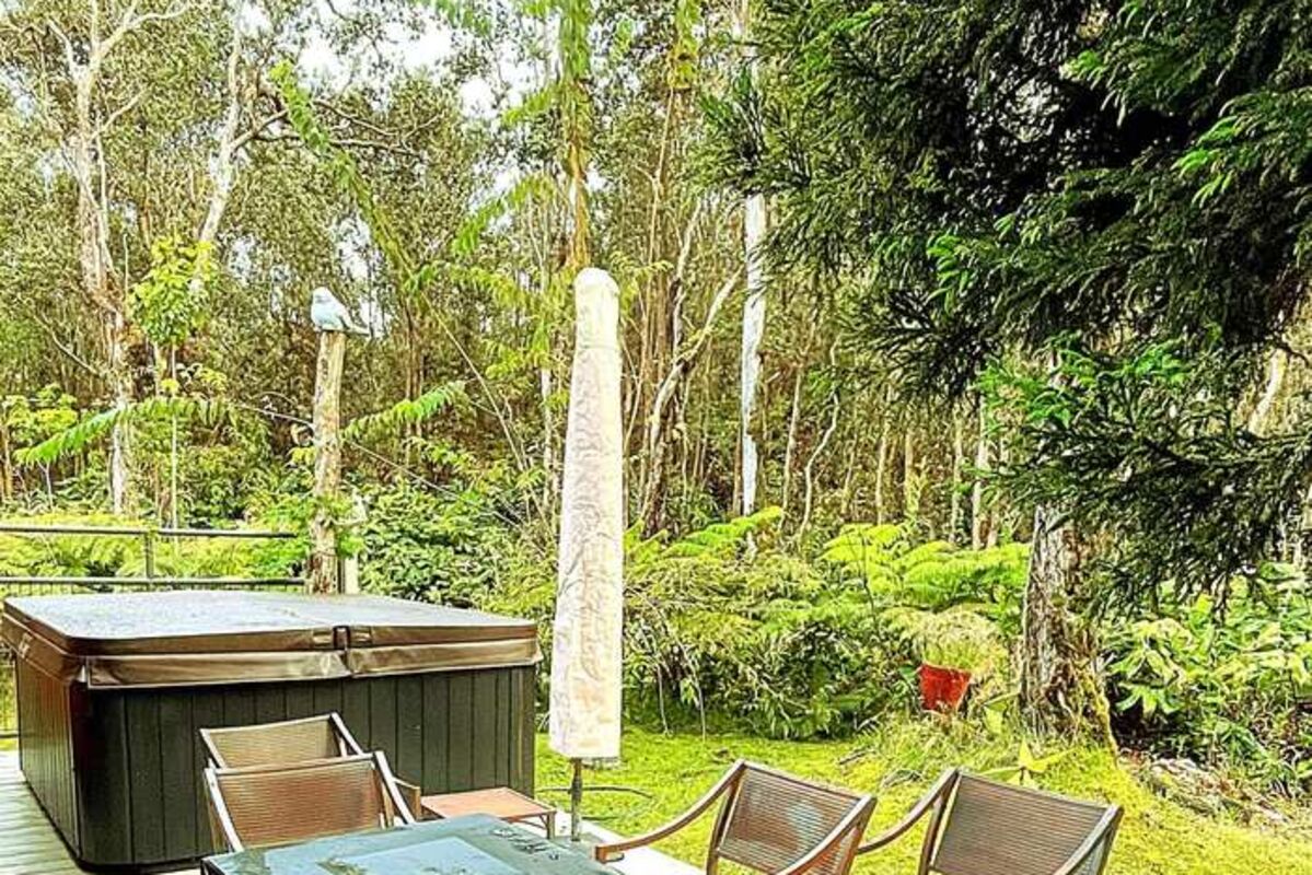 A deck with a fire pit and a jacuzzi in the rainforest of Hawaii.