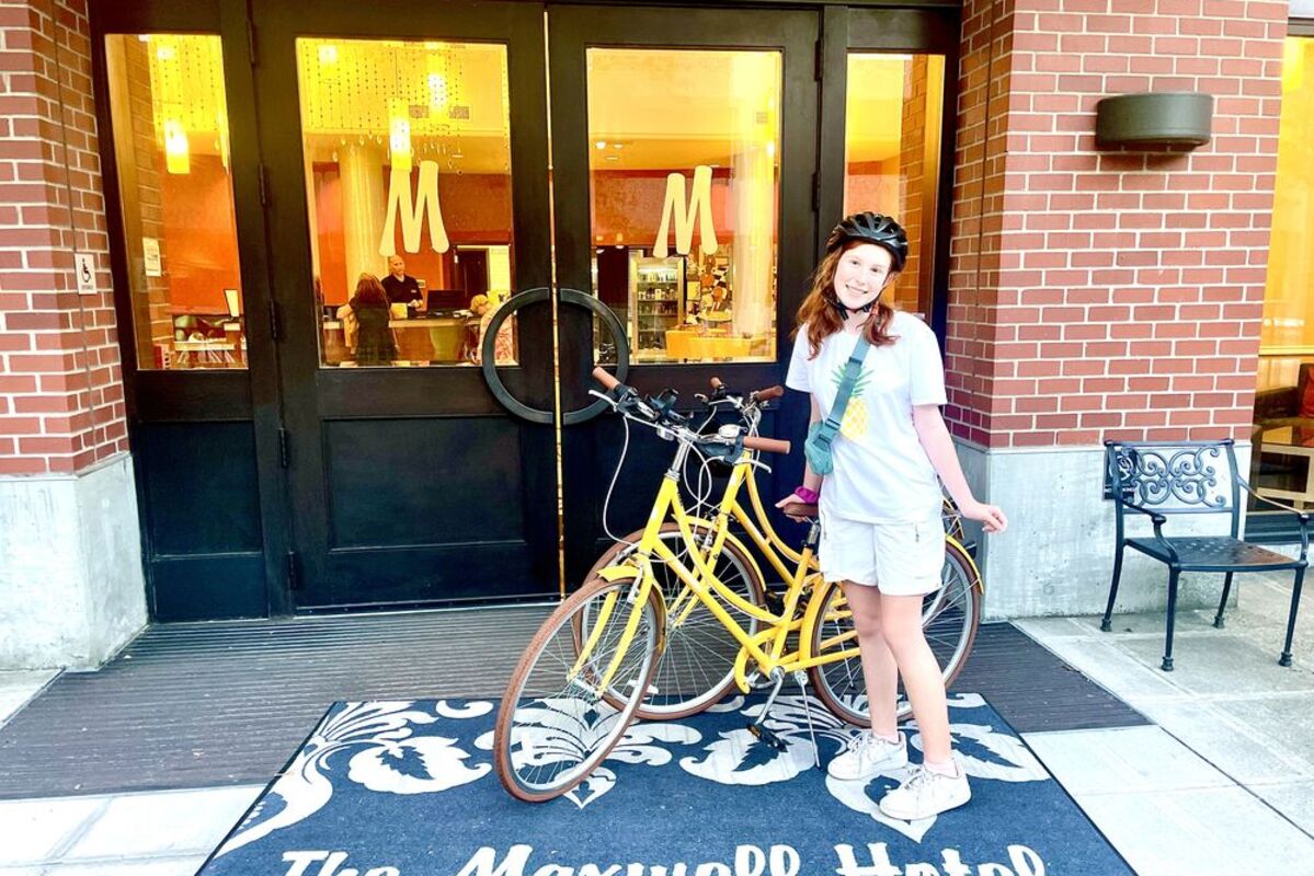 Girl in front of The Maxwell Hotel with a yellow beach cruiser.