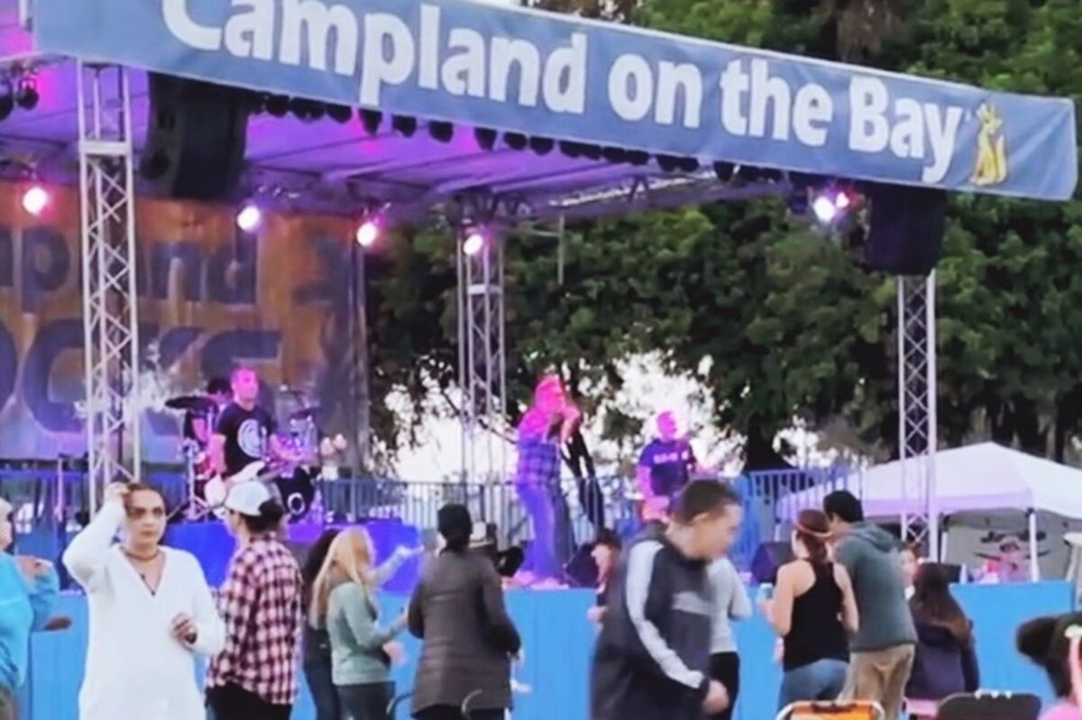 A grassy field with people on it in fromt of a stage at Campland On The Bay