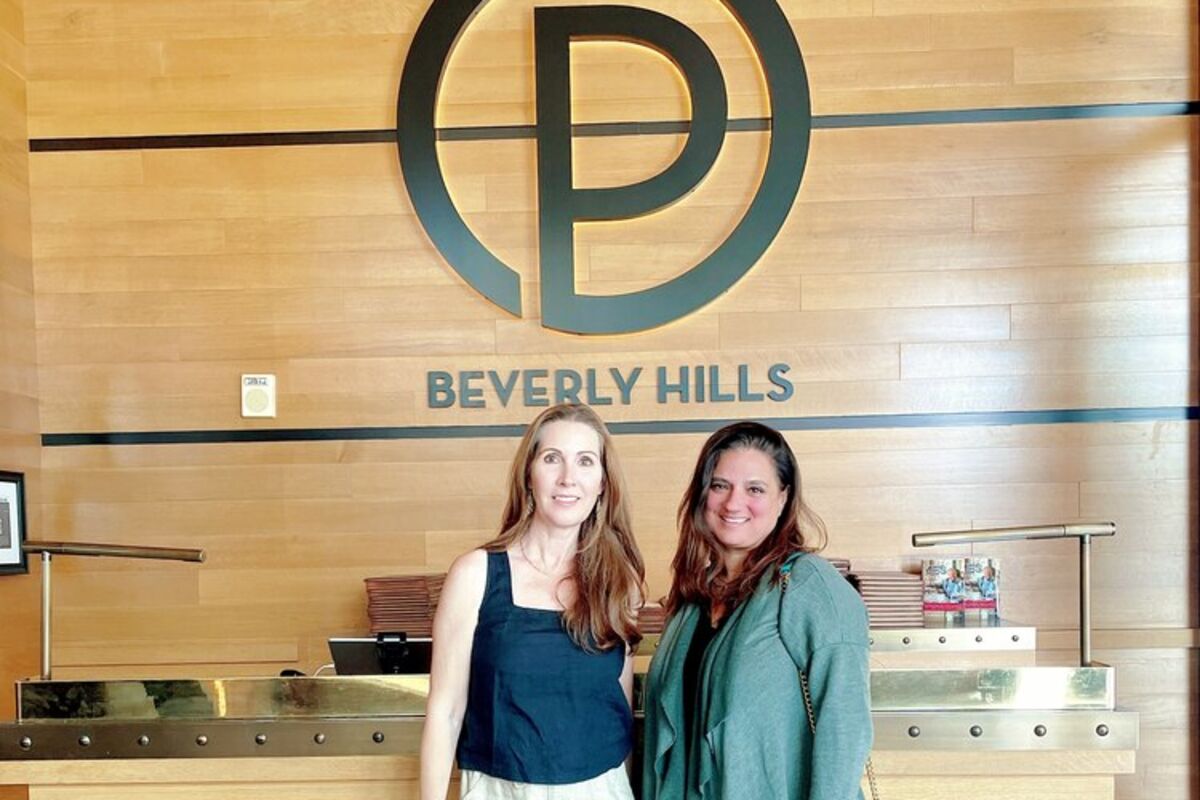 Women standing in front of Ocean Prime logo sign in restaurant in Beverly Hills